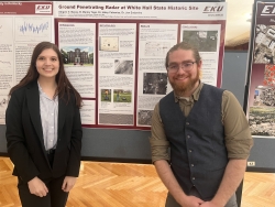 Two students pose in front of a research poster